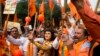 FILE - A man stands dressed as Hindu god Ram, center, as activists of right wing Hindu groups shout slogans demanding that a temple of Hindu god Ram be made at Ayodhya on the anniversary of the Babari Mosque demolition in New Delhi, India, Dec. 6, 2018. 