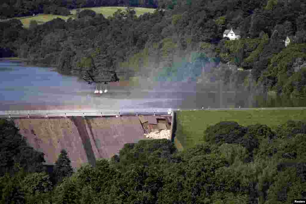 A Chinook helicopter drops sand bags on top of a dam after a nearby reservoir was damaged by flooding, in Whaley Bridge, Britain.