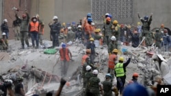 Pekerja penyelamat memberikan tanda dengan tandanya, meminta rekannya untuk menghentikan kegiatan saat evakuasi korban gempa di sebuah apartemen di jalan Amsterdam dan Laredo yang rubuh saat gempa mengguncang Mexico City, Meksiko, 21 September 2017