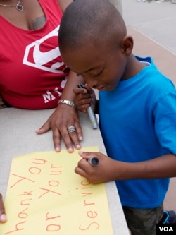 Camarion Hall leaves a note of support for Dallas police at a memorial site outside police headquarters in Texas, July 11, 2016. (M. O'Sullivan/VOA)