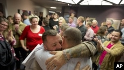 Chris Serrano, left, and Clifton Webb embrace after being married, as people wait in line to get licenses outside of the marriage division of the Salt Lake County Clerk's Office in Salt Lake City, Dec. 20, 2013.