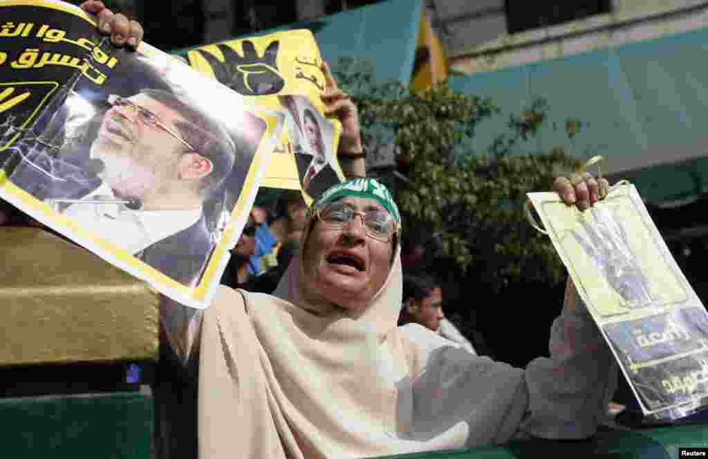 A supporter of ousted Egyptian president Mohamed Morsi cries while holding his poster and a "Rabaa" poster (R) outside the Egyptian High Court in Cairo, Nov. 4, 2013. 
