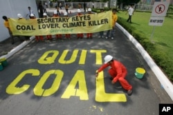 FILE - Activists from the environmentalist group Greenpeace paint the words "Quit Coal" on the driveway of the Department of Energy at Manila's Taguig city, June 3, 2008.