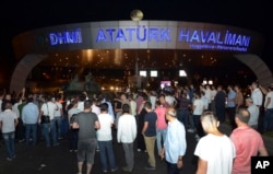People stand in front of a tank parked in the entrance to Istanbul's Ataturk airport, July 16, 2016. Members of Turkey's armed forces said they had taken control of the country, but Turkish officials said the coup attempt had been repelled early Saturday, state-run media said.