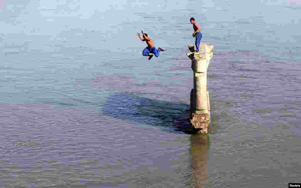 Seorang anak laki-laki terjun ke Sungai Sardaryab di hari yang panas di Peshawar, Pakistan, 1 Juni 2015.