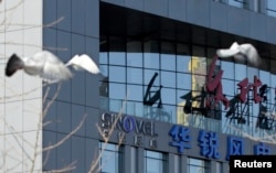 FILE - Birds fly past the company logo of Sinovel outside its head office in Beijing, Jan. 6, 2011.