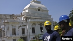 Workers from U.S. actor and Haiti's ambassador-at-large Sean Penn's charity J/P HRO (J/P Haitian Relief Organization) stand in front of the collapsed cupola of the condemned National Palace in Port-au-Prince, September 07, 2012. 