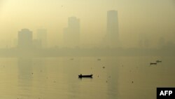 A fishing boat is seen in the morning general view of the city skyline covered by a smoggy haze in Mumbai, India, Jan. 29, 2016. 