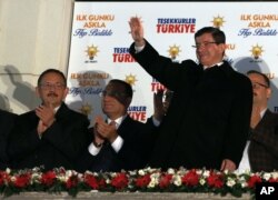 Turkish Prime Minister Ahmet Davutoglu salutes supporters gathered outside the ruling Justice and Development Party headquarters in Ankara, Turkey, Sunday, Nov. 1, 2015.