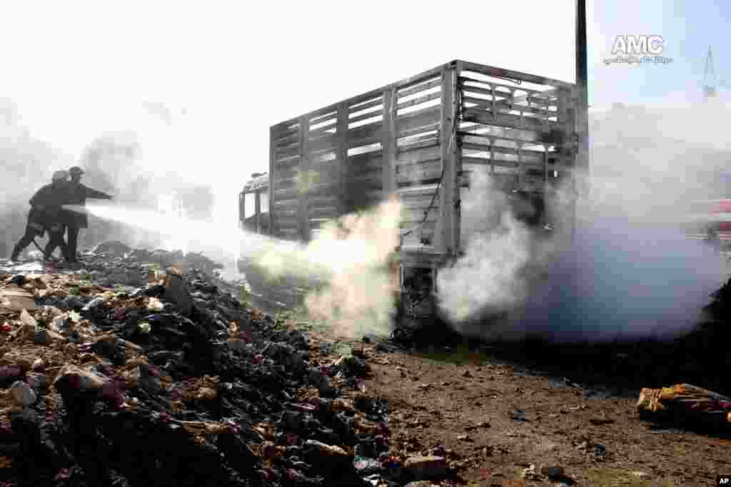 In this citizen journalism image, firefighters hose down burning vehicles after a Syrian aircraft pummeled an opposition neighborhood in Aleppo, Syria, Dec. 22, 2013.
