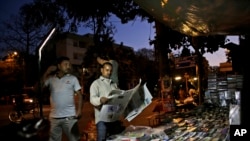 An Indian man reads a newspaper in front of a newsstand in New Delhi, India, March 15, 2016. Indian journalists say they face violence for questioning Prime Minister Narendra Modi or his government policies.