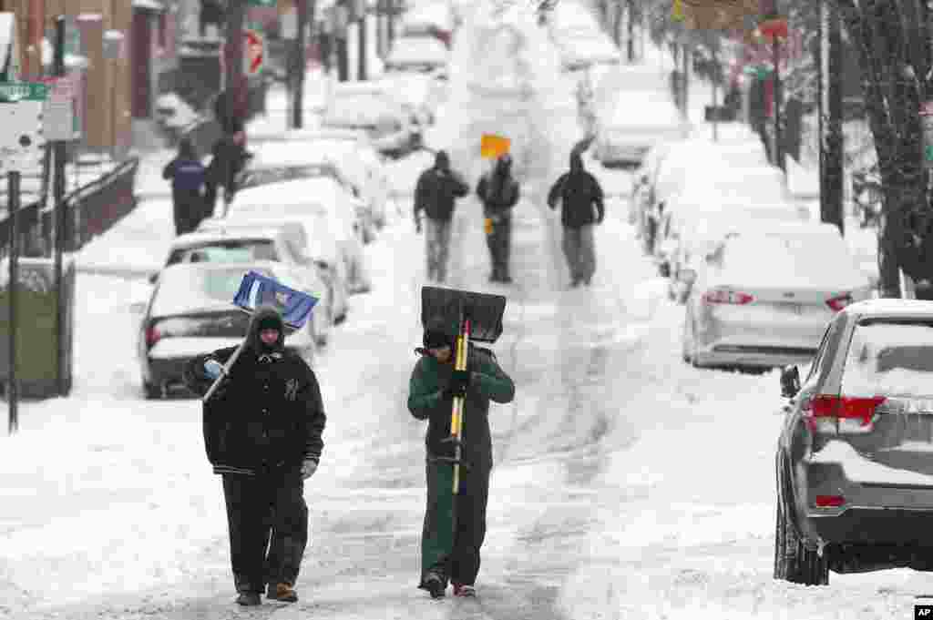 Men carry shovels a snow covered road after an overnight snowstorm in Hoboken, New Jersey, Jan. 27, 2015.