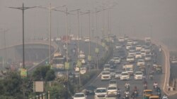FILE - Traffic moves on a smoggy morning in New Delhi, India, October 23, 2020.