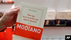 A man holds a book by French author Patrick Modiano at a book fair in Frankfurt, Germany, Oct. 9, 2014.