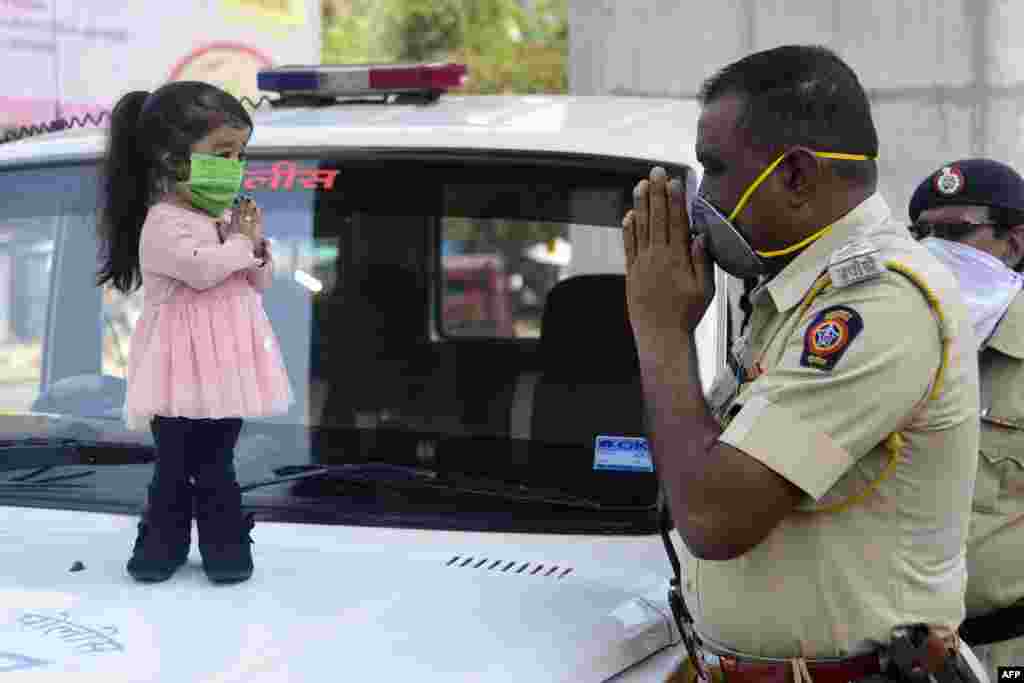 Guinness world record holder of the world&#39;s smallest living woman, Jyoti Amge (L), greets a police officer as she appeals citizens to stay inside their homes during a nationwide lockdown as a preventive measure against the coronavirus, in Nagpure, India.