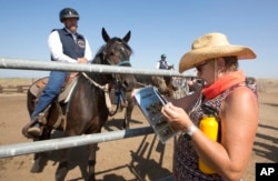 FILE - Prospective buyer Kimela Hancock looks over the program at the auction held by Wild Horse Program at the Sacramento County Sheriff's Department, Rio Cosumnes Correctional Center in Elk Grove, California, Sept. 10, 2016.