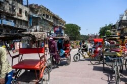 Pengemudi becak mengangkut penumpangnya di kawasan lama New Delhi, 19 April 2021. Ibu kota India akan memberlakukan lockdown selama seminggu mulai malam ini, untuk menahan lonjakan kasus COVID-19. (AFP)