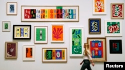 FILE - An employee poses with Henri Matisse's artworks at the Tate Modern Gallery in London, April 14, 2014.