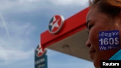 A woman with a sticker on her face reading, "We need $160 per month" protests at a Caltex petrol station in Phnom Penh May 14, 2014. 