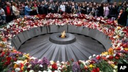 FILE - People lay flowers at a memorial to Armenians killed by the Ottoman Turks, as they mark the centenary of the mass killings, in Yerevan, Armenia, April 24, 2015.