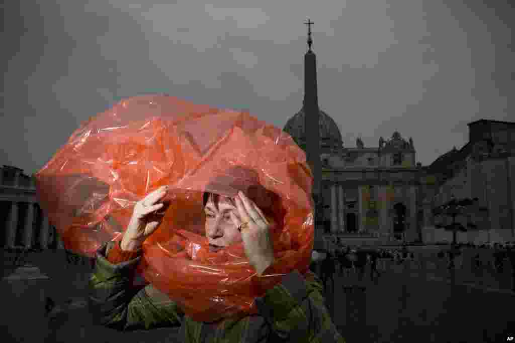 A woman takes cover from the rain in St. Peter&#39;s Square at the Vatican, the day ahead of the inaugural Mass of Pope Francis. In addition to more than 132 government delegations, the Vatican says 33 Christian delegations will be present, as well as representatives from Jewish, Muslim, Buddhist, Sikh and Jain communities.