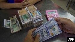 ရန်ကုန်မြို့ပေါ်ရှိ နိုင်ငံခြားငွေလဲလှယ်ရေးလုပ်ငန်းတခုမှာတွေ့ရတဲ့ အမေရိကန်ဒေါ်လာ ၁၀၀ တန်တချို့နဲ့ မြန်မာငွေ ၁၀၀၀ ကျပ်တန်များ (ဒီဇင်ဘာ ၁၆၊ ၂၀၁၆)