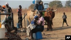 A woman smiles while playing with her baby at a water point on the outskirts of the capital Harare, Nov, 14, 2021.