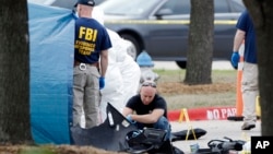 FBI crime scene investigators document the area around two deceased gunmen and their vehicle outside the Curtis Culwell Center in Garland, Texas, May 4, 2015.