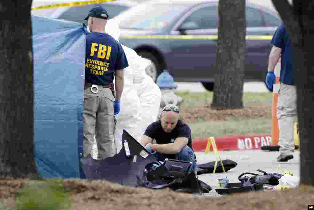 FBI crime scene investigators document the area around two deceased gunmen and their vehicle, outside the Curtis Culwell Center in Garland, Texas, May 4, 2015.