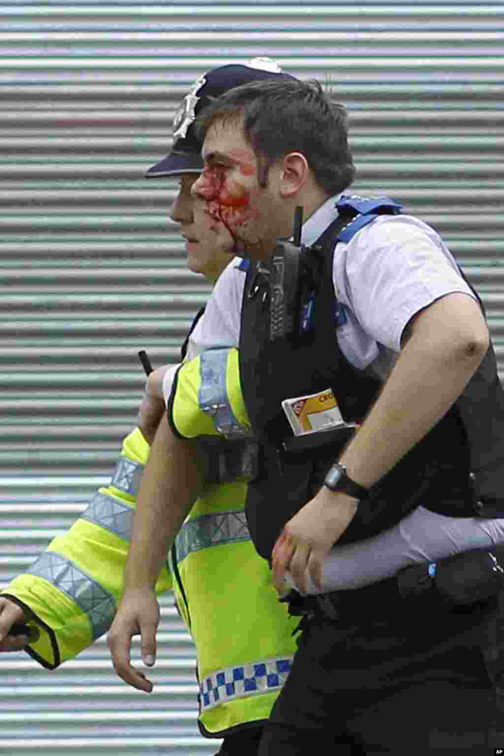 A police officer helps an injured officer as rioters gathered in Croydon, south London, Monday, Aug. 8, 2011. Violence and looting spread across some of London's most impoverished neighborhoods on Monday, with youths setting fire to shops and vehicles, du