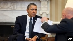 President Barack Obama studies a document held by Director of National Intelligence James Clapper during the Presidential Daily Briefing in the Oval Office, February 3, 2011.