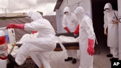 FILE - Health workers wearing Ebola protective gear remove the body of a man they suspect died from the Ebola virus, at a USAID, American aid Ebola treatment center on the outskirts of Monrovia, Liberia, Nov. 28, 2014.