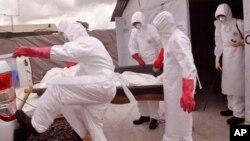 FILE - health workers wearing Ebola protective gear remove the body of a man they suspect died from the Ebola virus, at a USAID, American aid Ebola treatment center on the outskirts of Monrovia, Liberia, Nov. 28, 2014.