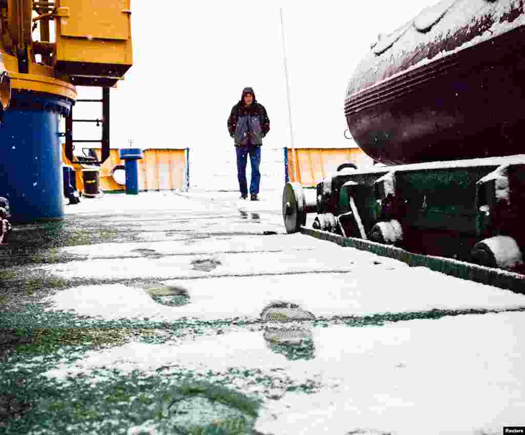 A crew member of the MV Akademik Shokalskiy walks on the snow-covered aft deck of the stranded ship in the Antarctic, Dec. 29, 2013. 