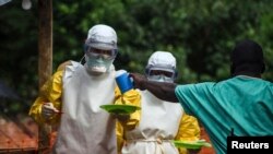 Medecins sans Frontieres (MSF) medical workers deliver food to patients kept in an isolation area at their Ebola treatment center in Kailahun on July 20.