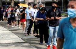 FILE - People queue up outside a quick test center to take their coronavirus disease (COVID-19) antigen rapid tests, in Singapore, Sept. 21, 2021.