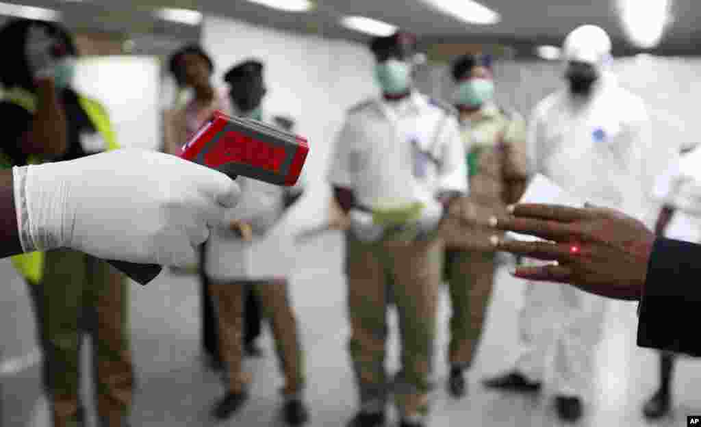 A Nigerian health official uses a thermometer on a worker at the arrivals hall of Murtala Muhammed International Airport, in Lagos, Nigeria, Aug. 4, 2014. 