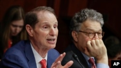 FILE - Sen. Ron Wyden, D-Ore., left, with Sen. Al Franken, D-Minn., right, join other Democratic senators at a hearing on Capitol Hill.