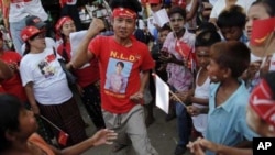 A man wearing a T-shirt bearing the image of Aung San Suu Kyi dances at campaign rally for the pro-democracy icon and her National League for Democracy, Rangoon, Burma, March 30, 2012. 