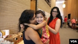 Gayatri “Genny” Joshi greets the daughter of her fellow SAYHU co-founder at the summer institute. (E. Sarai/VOA)