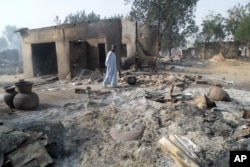 FILE - A man walks past burnt out houses following an attack by Boko Haram in Dalori village near Maiduguri, Nigeria.