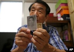 Lee Soo-nam, 76, shows photos of his brother Ri Jong Song in North Korea during an interview at his home in Seoul, South Korea, Aug. 17, 2018.