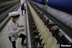FILE - A worker disentangles wool yarn at a spinning machine at a factory owned by Hong Kong's Novetex Textiles Limited in Zhuhai City, Guangdong province, China, Dec. 13, 2016.