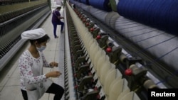FILE - A worker disentangles wool yarn at a spinning machine at a factory owned by Hong Kong's Novetex Textiles Limited in Zhuhai City, Guangdong province, China, Dec. 13, 2016. Novetex is set to open a factory in Hong Kong that will use new technology to separate fabric blends in waste garments and produce yarn. 