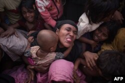 Rohingya Muslim refugees react as police and officials attempt to control a surging crowd as they wait to be called to recieve food aid of rice, water, and cooking oil in a relief centre at the Kutupalong refugee camp in Cox's Bazar on November 28, 2017.
