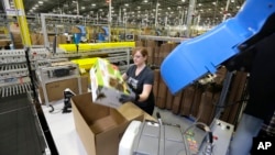 FILE - A worker places an item in a box for shipment, at a Amazon.com fulfillment center in DuPont, Washington. 