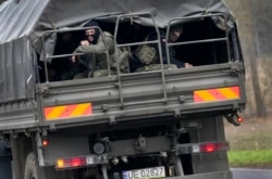 Polish soldiers sit on an army vehicle as they drive past a check point close to the border with Belarus in Kuznica, Poland, Nov. 16, 2021.