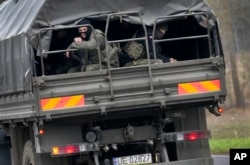 Polish soldiers sit on an army vehicle as they drive past a check point close to the border with Belarus in Kuznica, Poland, Nov. 16, 2021.