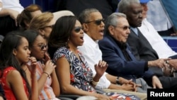 U.S. President Barack Obama and his family react along with Cuban President Raul Castro to an exhibition baseball game in Cuba.