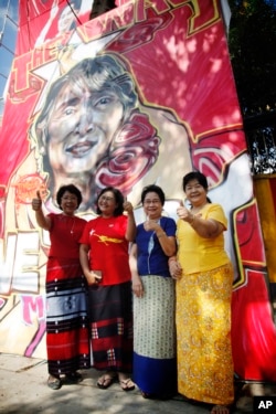 Members of Myanmar opposition National League for Democracy party pose for photos in front of a graffiti art depicting party leader Aung San Suu Kyi created by artist Arker Kyaw outside the party's headquarters in Yangon, Myanmar, Nov 13, 2015.